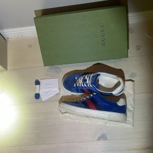 Blåa extremt sällsynta Gucci Ace i mocka - Säljer ett par blåa Gucci Ace sneakers i mjuk mocka, dom är super sällsynta och får inte att få tag på nya, jag köpte dom för 9000 helt nya ifrån vestaier coollective som är en mer exuluksiv begagnande hemsida som säljer kläder och skor, det ör äktehets kollat och dom är såklart äkta kom gärna vid minsta fråga eller om ni vill ha fler bilder🌟🌟🌟