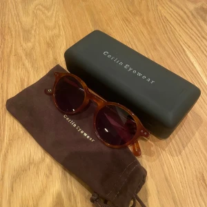Colin Eyewear - Snygga runda solglasögon från Corlin Eyewear i modellen Lia Havana Black. Bågarna är bruna med sköldpaddsmönster och svarta glas. Kommer med originalfodral och putsduk. Super snygga och passar både tjej och kille
