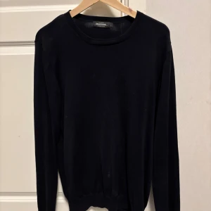 Svart bomullströja från Dressmann - En stilren svart tröja från Dressmann i Supima-bomull. Tröjan har rund halsringning, lång ärm och en klassisk passform som funkar till allt. Enkel och clean design utan mönster eller detaljer, perfekt för dig som gillar basic och tidlöst.