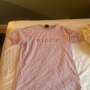 Ljuslila t-shirt från NICCE - Säljer en ljuslila t-shirt från NICCE med broderad logga framtill. Klassisk rund halsringning och korta ärmar. Skön och mjuk i bomull, perfekt för en chill och stilren look. Använd runt 4-5 gånger. Pris kan diskuteras 💞