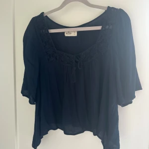 Mörkblå blus från Hollister - Säljer en mörkblå blus från Hollister med fyrkantig ringning och dekorativ knytning framtill. Blusen har trekvartsärmar och är tillverkad i ett lätt, luftigt material som ger en skön känsla. Perfekt för dig som gillar en avslappnad och bohemisk stil. Pris går att diskutera 