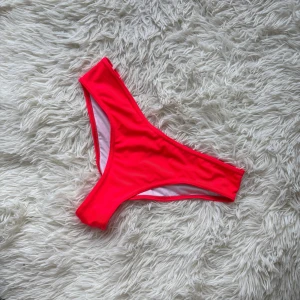 Rosa bikinidel från PrettyLittleThing - Säljer en snygg bikiniunderdel i stark rosa färg från PrettyLittleThing. Modellen är klassisk med hög skärning och mjukt, stretchigt material som sitter bekvämt. Perfekt för strandhäng och poolparty i sommar! Materialet är 78% polyamid och 22% elastan.