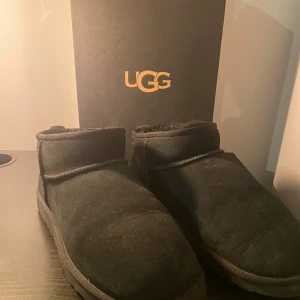 Svarta UGG boots i mocka - Svarta UGG boots med rund tå och platt sula, tillverkade i mjuk mocka med fluffigt foder på insidan. Klassisk UGG-logga baktill och enkel design som ger en chill vibe. Perfekt för kalla dagar när du vill ha det extra bekvämt. 👍