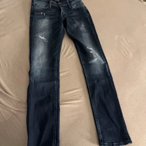 Mörkblå jeans från Jack & Jones - Snygga mörkblå jeans från Jack & Jones med slitna detaljer och lätt tvättad look. Är mer åt slim fit hållet! 