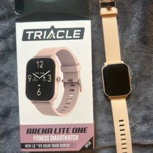 Arena Lite One Fitness Smartwatch - Triacle Arena Lite One är en stilren fitness smartwatch med 1,8'' IPS färg touchskärm. Klockan har aktivitetsmätning, pulsmätare, stegräknare och andra smarta funktioner. Skärmen och armbandet är i fint skick utan synligt slitage. Perfekt för träning och vardagsbruk. Använd ca en vecka så dom är som ny. Köpt för 899