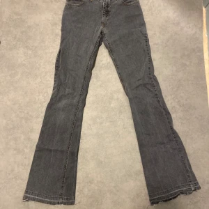 Vintage Grå bootcut jeans från Milas Jeans - Snygga grå jeans från Milas Jeans med bootcut passform och råa, jeansen är i okej skick, skicket visas i bilderna. Klassisk femficksmodell med kontrastsömmar och tydlig logga på bakfickan. Jeansen har en rak siluett upptill och utsvängda ben, perfekt för en avslappnad look. Längd 104cm, midja 34cm, innerben 86cm. Kolla gärna in profilen för liknande produkter och skriv vid minsta lilla fråga 