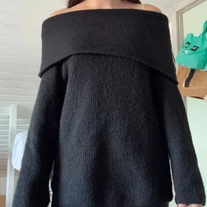 Svart offshoulder stickad tröja H&M - Mysig svart stickad tröja från H&M med bred offshoulder-krage. Tröjan har lång ärm och en loose passform som ger en avslappnad vibe. Perfekt för kyliga dagar när du vill vara både bekväm och snygg.