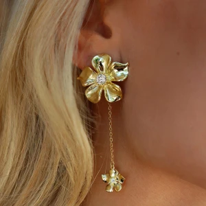 Guldiga Ioaku blommiga örhängen  - Superfina örhängen i guld med blommformad design och glittrande detalj i mitten. De har en lång kedja som hänger ner med en mindre blomma längst ner, vilket ger en cool och elegant vibe. Perfekt för dig som vill sticka ut med något unikt och trendigt. Från Ioaku, typ aldrig använda! By pris 599kr mitt pris 400