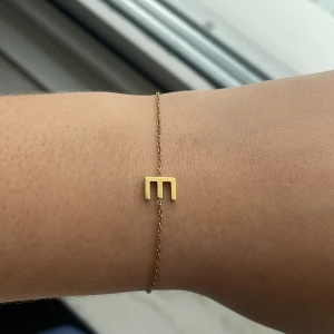 Guldarmband med bokstav från Edblad  -  Armband i guld från Edblad med bokstaven '’E”. Tunn kedja och justerbar längd. Den är helt rostfri och tål vatten. Ordinarie pris är 300 