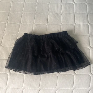 Svart volangkjol från IVIVI S/M - Supersöt svart höstig kortkjol från IVIVI med flera lager volanger och diskret prickigt mönster. Kjolen har elastisk midja och är gjord i ett tunt, lätt material som ger en luftig känsla. Säljs då den inte andvänds längre. Priset kan självklart diskuteras ❤️