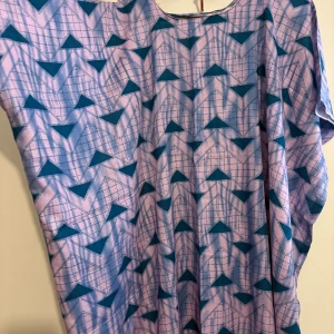 Somali baati- Lila och blå mönstrad kortklänning - Säljer en loose-fit kortklänning i lila med blått geometriskt mönster. Klänningen har rund halsringning och vida, korta ärmar. Perfekt för dig som gillar färg och unika prints. Storlek-one seize 