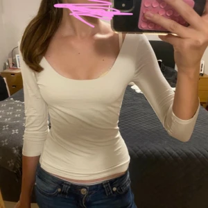 Krämvit trekvartslång topp  - Säljer en vit trekvartslång topp från Gina i storlek Xs💗. Toppen har en djup rundad urringning och sitter ganska tight💗aldrig använd! Pris kan diskuteras.
