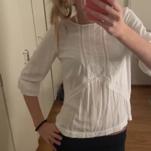 Vit blus med spetsdetaljer - Säljer en söt vit blus med spetsdetaljer framtill och 3/4-ärmar. Storlek xs men sitter lite lösare skulle jag säga❣️