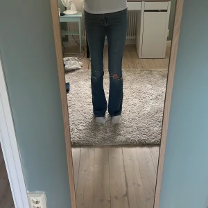 Blå bootcut jeans - Snygga blå bootcut jeans från Gina tricot med slitna detaljer och hål vid knäna. Klassisk femficksmodell med normal passform och dragkedja. Jeansen har en cool tvättad look och är tillverkade i jeansmaterial. Dem har en mindre defekt men inget man tänker på!☀️