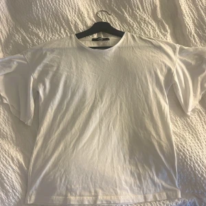 Vit basic t-shirt från Bikbok - En enkel vit t-shirt från Gina Tricot med rund hals och korta ärmar. Modellen är rak och lite loose fit, perfekt till jeans eller mjukisbyxor. T-shirten är gjord i mjuk bomull och har en clean, stilren look. 