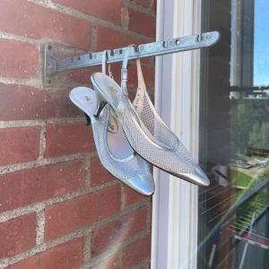 Silvriga pumps med spetsig tå - Säljer ett par silvriga pumps från Maich med spetsig tå och låg klack. Skorna har ett meshmönster på ovansidan och en snygg rem runt hälen med spänne. Materialet är syntet med metallicfinish som ger extra glans. Perfekt för dig som gillar att sticka ut med coola detaljer.