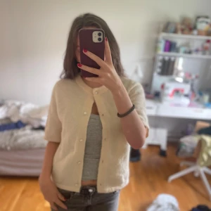 Ljugul kofta med kort ärm från Gina Tricot - Superfin gul  kofta från Gina Tricot med korta ärmar och rund hals. Koftan är stickad i mjukt material och har knappar framtill.