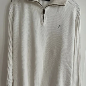 Vit stickad half zip från Peak Performance - Vit stickad tröja från Peak Performance i storlek XL. Tröjan har en half zip-dragkedja vid halsen, ribbade detaljer längs ärmarna och diskret logga på bröstet. Perfekt för lager-på-lager under kyliga dagar.