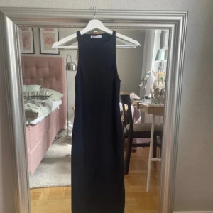 Svart ribbad klänning från Zara - Säljer en svart, tight och ribbad klänning från Zara. Klänningen är ärmlös med hög hals och har en kroppsnära passform som slutar strax under knäna. Perfekt för dig som gillar en stilren och enkel look.