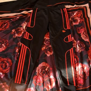 Adidas svarta träningsbyxor XS passar S också - Svarta träningsbyxor från Adidas med röda detaljer och klassiska ränder längs benen. Byxorna har elastisk midja och smal passform. Adidas-logga på låret och coola röda linjer som ger en sportig vibe.