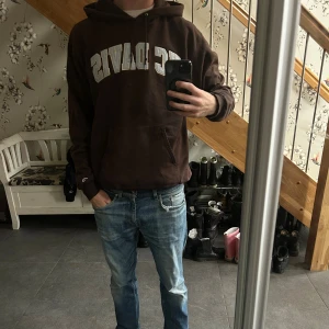 Brun hoodie från Champion UC Davis - Säljer en as fett vintage brun hoodie från Champion med UC Davis-tryck över bröstet. Klassisk känguruficka framtill, huva med snörning och mjukt material. Perfekt för dig som gillar college-vibe och avslappnad stil.