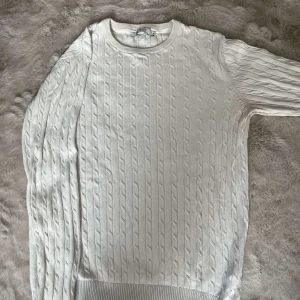 Vit kabelstickad tröja Jack & Jones - Kabelstickad vit tröja från Jack & Jones Premium. Klassisk rund halsringning och ribbade muddar vid ärmslut och nederkant. Perfekt för lager-på-lager och enkel att matcha med jeans eller chinos.