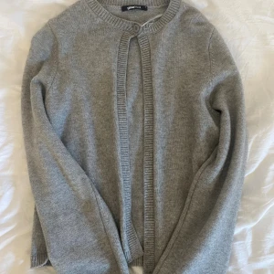 Grå kofta från Gina Tricot - Mysig grå kofta från Gina Tricot med rund halsringning och ribbade kanter. Koftan har en enkel knapp upptill. Har ett litet hål i armhålan, kontakta för mer info 💗