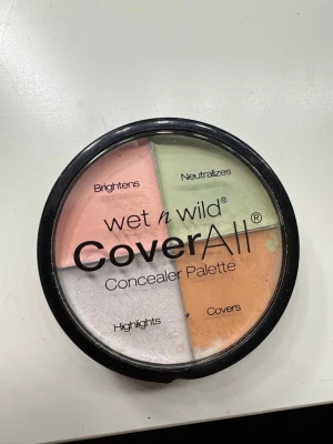 Wet n Wild CoverAll Concealer Palette - Fyrdelad concealerpalett från Wet n Wild med krämiga nyanser: persikorosa för att ljusa upp, grön för att neutralisera rodnad, beige för att täcka och vit för highlight. Perfekt för att skapa en jämn bas och dölja ojämnheter. Rund dosa i plast med genomskinligt lock.