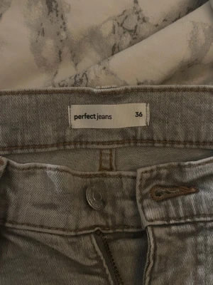 Ljusgrå bootcut jeans från Gina tricot - Säljer ett par ljusgrå jeans från Perfect Jeans i storlek 36. Modellen har bootcut-snitt.Jeansen är tillverkade i jeansmaterial och har en snygg, ljus tvätt som passar till många olika stilar.