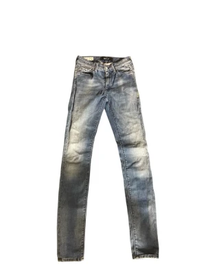 Replay blå raka jeans - Säljer ett par blå jeans från Replay med klassisk femficksdesign och raka ben. Jeansen har en snygg tvättad look med slitningar och är tillverkade i mjukt denimtyg. Perfekta för dig som gillar en avslappnad men ändå stilren vibe.