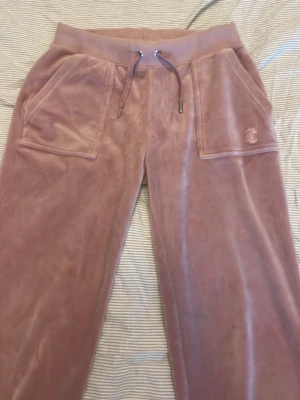 Rosa Juicy Couture byxor🌸 - Säljer ett par Juicy byxor i helt ok skick som ni ser på bilderna så är snöret nipprigt en metal grej på snöret saknas men annars i bra skick. För frågor skriv privat försöker alltid att skicka paketen så snabbt som möjligt💕 Säljer bara via (INSTABOX)🌸