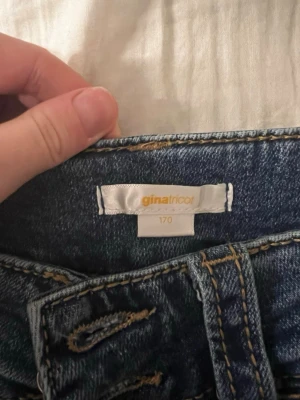 Blå jeans från Gina Tricot, storlek 170 - Snygga blå jeans från Gina Tricot i klassisk modell med fem fickor och kontrastsömmar. Jeansen har normal passform med lite utsvängande. Perfekta till en avslappnad stil och funkar året runt.