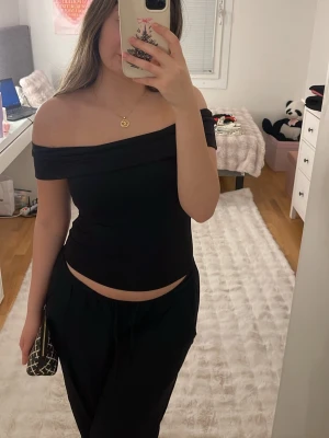 Svart offshoulder topp från Ally - Säljer en svart offshoulder topp från Ally. Toppens axelbandslösa design ger en snygg och stilren look. Materialet är mjukt och stretchigt, vilket gör den bekväm att bära. Perfekt att styla med både jeans och kjol för en trendig outfit.