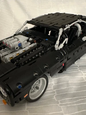 Lego Technic 42111  Dom’s dodge charger byggsats med leksaksbil  - Säljer en svart dunväst med coola detaljer och sportig vibe, byggd av LEGO Technic-delar. Västen har en unik form med synliga konstruktionselement och inslag av grått och silver. Perfekt för dig som gillar att sticka ut och vill ha något riktigt annorlunda i garderoben.  Utan förpackning och utan instruktioner, passar för samling eller som present. 