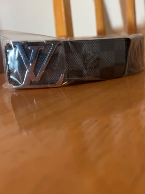 L-v Bälte Svart Rutig - Säljer ett helt nytt riktigt snyggt svart  L-v bälte med silver logga.