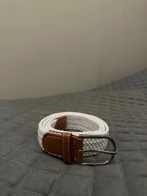 Vit flätat bälte - Tja det är helt nytt från Bältgallerian. Det är 105cm långt och 3,5cm brett. Det är i ett elastiskt material så passar större storlekar också. Om du inte gillar den här färgen så finns det många flera att välja mellan. Vid köp av bundle så blir kostnaden billigare.