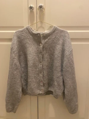 Grå stickad kofta med knappar - Mysig grå stickad kofta med knäppning framtill. Använd 2 gånger, så den är i mycket bra skick.