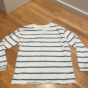 Randig långärmad topp från lager 157 - Säljer en vit långärmad topp från lager 157 i storlek XS. Toppen har svarta horisontella ränder och är gjord i 100% bomull, vilket gör den mjuk och skön att ha på sig. Perfekt till jeans eller kjol.