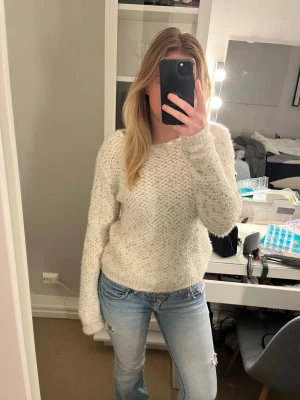 Vit stickad tröja med pärlor - Står storlek L men känns som S-M! Mysig vit stickad tröja med pärlor och glittriga detaljer vid halsringningen. Tröjan har lång ärm och en fluffig, lite lös passform som känns både chill och trendig. Perfekt för kalla dagar när du vill vara både varm och snygg.
