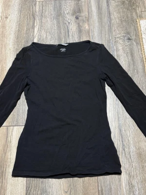 Svart långärmad topp från H&M XS - En enkel och stilren svart långärmad topp från H&M i mjuk pima bomull. Modellen har rund halsringning och en tight passform som sitter snyggt på kroppen. Perfekt basplagg att matcha med allt i garderoben.
