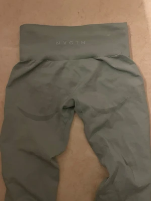 Gröna leggings från NVGTN - Snygga gröna leggings från NVGTN med tight passform. De är tillverkade i ett stretchigt material som sitter skönt och formar sig efter kroppen. Perfekta för träning eller chill dagar. Diskret logga baktill på midjebandet. Används få gånger. I storlek S. Samma träningstights som på bild 1 fast gröna!!! 💓 