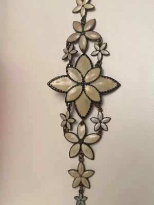 Blommigt smycke i metall och pärlemor - Unikt smycke med stora och små blommor 