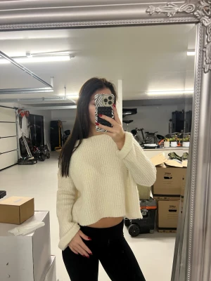 Vit croppad stickad tröja - Säljer en vit croppad stickad tröja med ribbad struktur och långa ärmar. Tröjan har en loose passform och är perfekt för dig som gillar en chill och avslappnad stil. Mjuk och skön, passar till svarta jeans eller leggings.