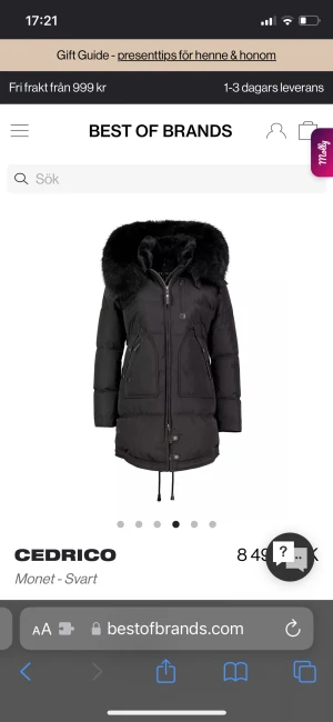 Svart pufferjacka med fuskpäls från Cedrico - Svart pufferjacka från Cedrico med stor huva och bred fuskpäls runt kragen. Jackan har dragkedja, knappar, snörning i midjan och flera fickor med dragkedja. Lång modell som håller dig varm och stilsäker under kalla dagar. Använd en vinter och är köpt från johnells för 8500kr. Vid snabbaffär kan priset diskuteras. Modellen heter monet