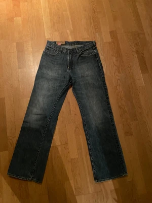 Blå loose fit jeans från GAP - Säljer ett par klassiska blå jeans från GAP med loose fit och raka ben. Jeansen har fem fickor, slitna detaljer och en cool vintage-vibe. Sitter skit snyggt och har inga defekter förutom lite heelbite.
