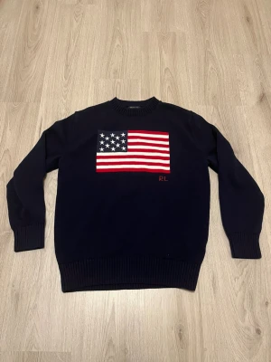 Marinblå tröja från Ralph Lauren. Med den amerikanska flaggan på  - Marinblå tröja från Ralph Lauren. Med den amerikanska flaggan på. Tröja är i jättebra skick 