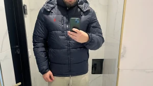 Mörkblå pufferjacka från Polo Ralph Lauren - Snygg mörkblå pufferjacka från Polo Ralph Lauren med röd logga på bröstet. Jackan har huva, dragkedja framtill och två sidofickor med dragkedja. Tillverkad i polyester och fodrad för extra värme. Perfekt för kalla dagar och har en clean, modern look.