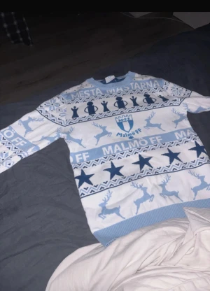 Malmö FF jultröja XS med mönster - Säljer en vit och ljusblå stickad jultröja från Malmö FF i storlek XS. Tröjan har coolt mönster med stjärnor, pokaler och renar samt texten 'Mesta Mästarna'. Ribbad hals, ärmslut och nederkant. Perfekt för dig som älskar fotboll och vill sticka ut på julen.