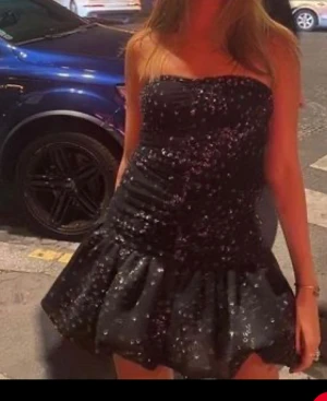 Nyårsklänning maje roxanne - Supersnygg svart axelbandslös kort klänning med glittriga paljetter över hela tyget. 