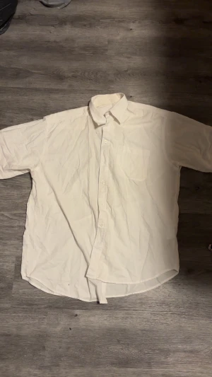 Vit klassisk skjorta från Color - Enkel och stilren vit skjorta från Color med klassisk krage, bröstficka och knäppning framtill. Skjortan är tillverkad i bomull och polyester, perfekt för en clean och tidlös look.